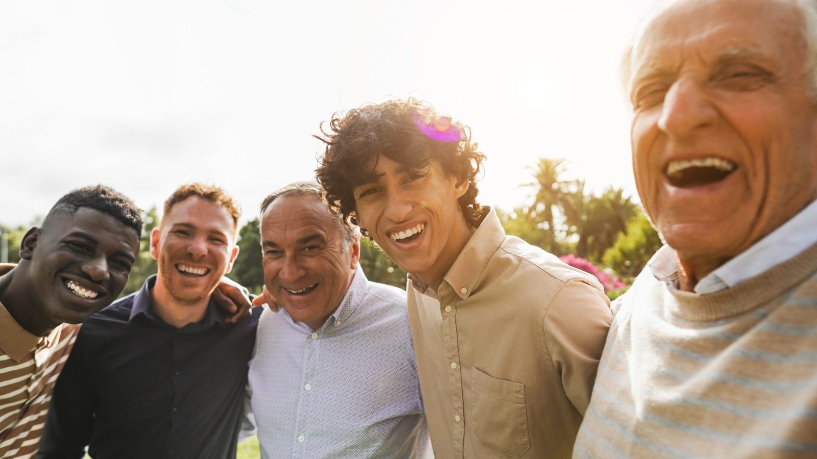Multi generational men smiling in front of camera - Male multiracial group having fun togheter outdoor - Focus on rught boy face